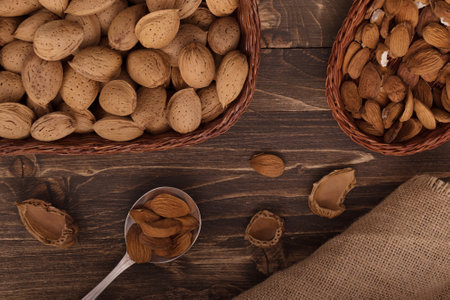 Flat lay of almonds in the wicker plates with other accessories on brown wooden background top view. 2の写真素材