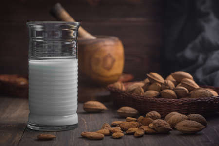 Almond milk in glass with almonds on rustic wooden background in low key. close up side view. 2の写真素材