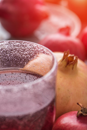 A glass of pomegranate juice on fresh pomegranate fruits background. Selective focus.の写真素材