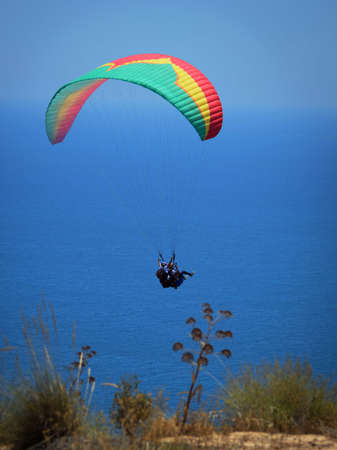 Flying tandem paragliders in the sky over the sea and near the mountains, beautiful sea viewの写真素材