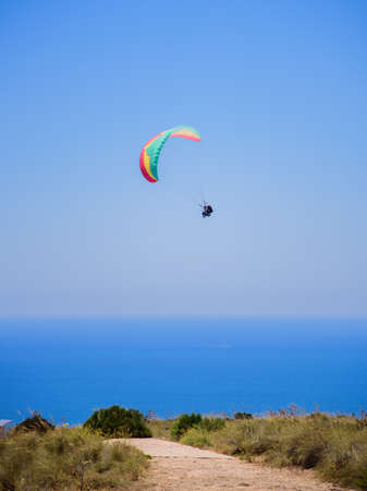 Flying tandem paragliders in the sky over the sea and near the mountains, beautiful sea viewの写真素材