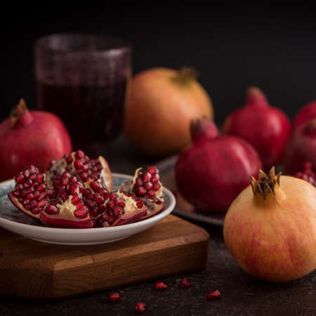 A glass of pomegranate juice with fresh pomegranate fruits and seeds on rustic background. Close up Side view. Low keyの写真素材