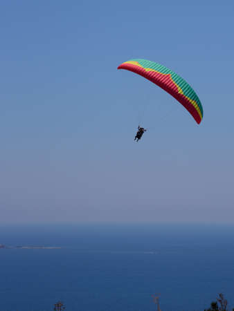 Flying tandem paragliders in the sky over the sea and near the mountains, beautiful sea viewの写真素材