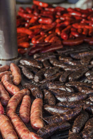 Different kinds of fresh spanish sausages on big round grill and hanging in bunches. Soft focus.の写真素材