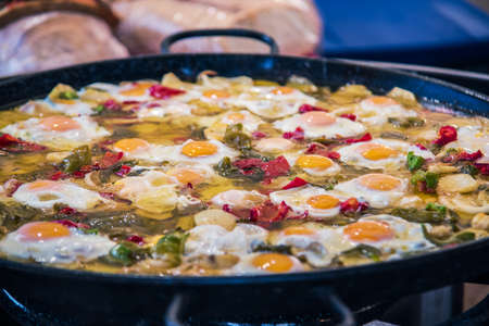 Traditional spanish big pan of fried eggs, paprika, dried tomatoes and parsley. Selective focus.の写真素材