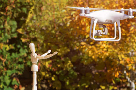The AI serviceman doll is meeting his drone return and landing. Toned on trees background.