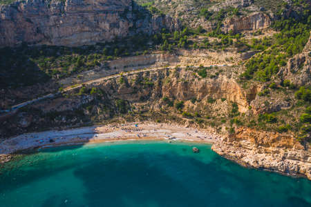 Aerial drone view on cozy beach Cala Moraig, Valencia community, Spain with some tourists. Summer sunny day. Cala Moraig, Valencia community, Spainの写真素材
