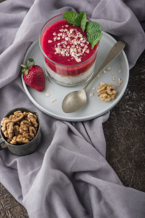Top view of Homemade pudding of Chia seeds and almond milk with cereals and puree strawberry with walnuts and mint in glass jar. Vegan healthy morning breakfast or superfood dessert on dark stone background.の写真素材