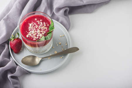Top view of Homemade pudding of Chia seeds and almond milk with cereals and puree strawberry with mint in glass jar. Vegan healthy morning breakfast or superfood dessert on white background.の写真素材