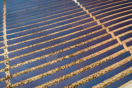 Drone aerial shooting of solar power farm raws of reflective panels. At cloudy day in Spain.