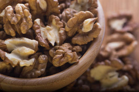 Top close up view of group of large dried ukranian russian peeled Walnut kernels in a wooden bowl on rustic background. Selective focus.の写真素材
