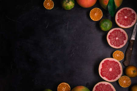 Low key top view of citrus fruits background. Mix of cutted grapefruits and mandarins. Flat lay composition with copy space.の写真素材