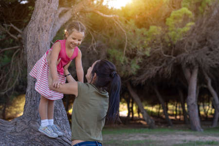 Beautiful mother and her little daughter outdoors. Beauty Mum and her Child playing in Park together at sunset. Outdoor Portrait of happy family. Mother's Day.の写真素材