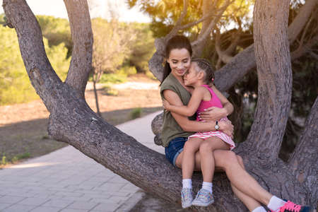 Beautiful mother and her little daughter outdoors. Beauty Mum and her Child playing in Park together at sunset. Outdoor Portrait of happy family. Mother's Day.の写真素材