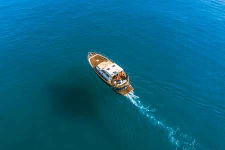 Small fishing boat is sailing on the shallow of mediterranean sea at sunny day- Aerial image with...