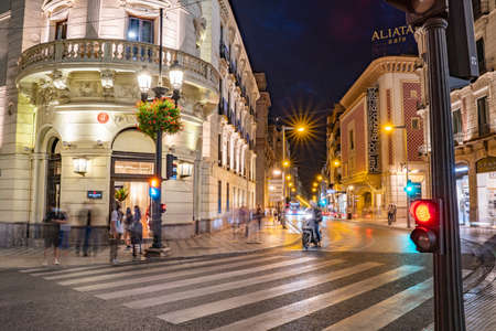Night photo of entrance of NH Collection Victoria Hotel, street Recojidas of Granada 30.Sept.2020 Albacin, Granada, Spain. Long light trails and blurred people motions.のeditorial素材