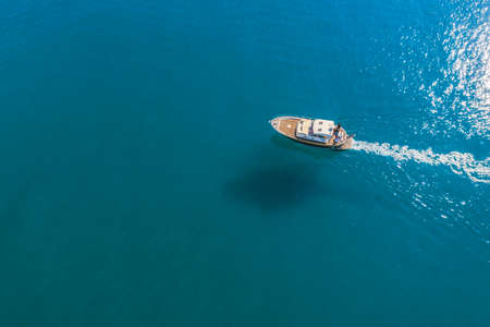Small fishing boat is sailing on the shallow of mediterranean sea at sunny day- Aerial image with copy space.のeditorial素材