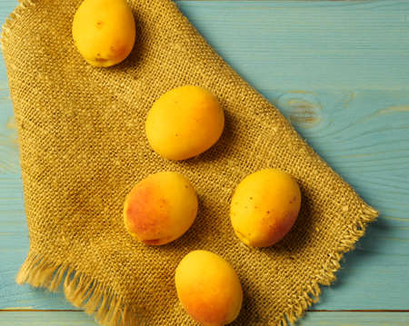 Individual apricots on a burlap and blue-gray wooden background. Proper nutrition, Lifestyle, Close-up,のeditorial素材