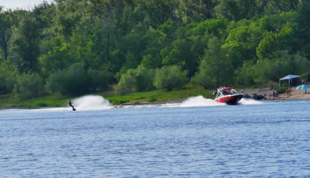 Water skier rides on the river in tow behind the boat. Lifestyle. Sports and recreation,の写真素材