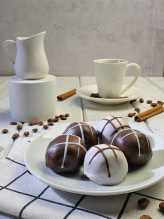 Chocolate truffles on a white plate and a cup of coffee