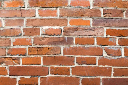 An old brick masonry wall of a warehouse made of red brick.