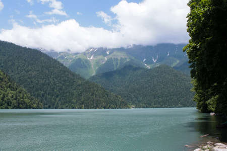 High mountain blue lake and mountains in the clouds with snow on the peaks. The mountains are...