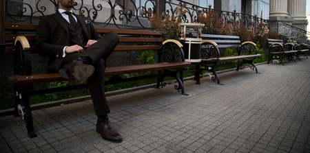 Male model in a suit sitting on a benchの写真素材