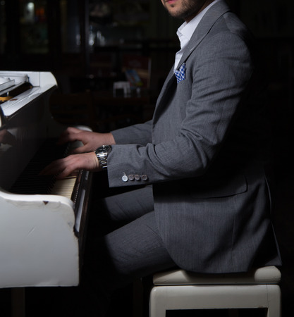 Male model in a suit posing with a pianoの写真素材
