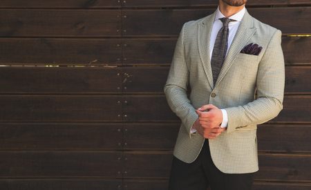 Male model in a suit posing in front of a wooden wallの写真素材