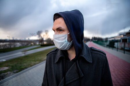 Young man with a medical face mask outdoor photo.Air pollution coronavirus protection concept.