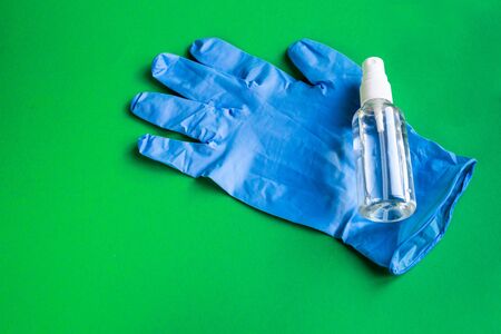 Hand picked sanitizer and blue medical glove as protection against coronavirus on green backgroundの写真素材