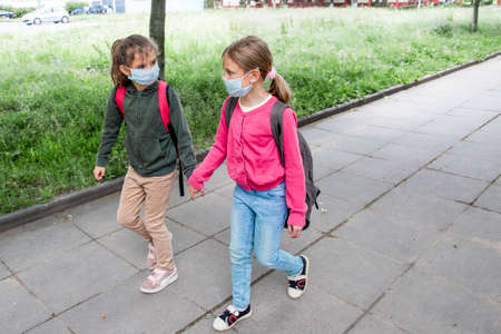 Two girls wearing protective face mask and going back to school during coronavirus pandemic.の写真素材