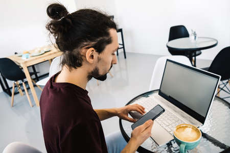 Freelance man working with laptop and smart phone at cafe with coffe.の写真素材