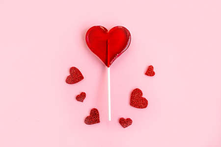 Red lollipop and hearts on pink background. Love and sweets concept. Flat lay, top view, copy spaceの写真素材