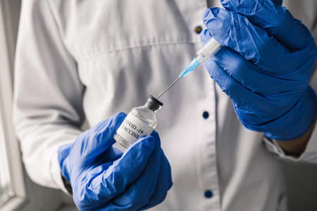 Close Up Doctor Wearing Blue Gloves Draws The Covid-19 Vaccine into a Syringe, Preparing for Vaccination Shot. New normalの写真素材