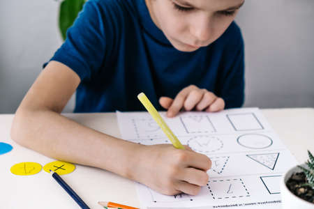 Boy focusing on his homework while sitting at desk.の写真素材