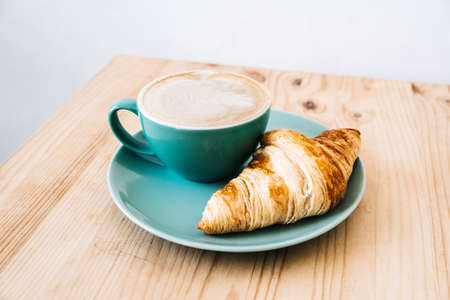Cappuccino and croissant on wooden table. Morning breakfast conceptの写真素材