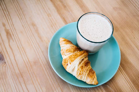 Cappuccino and croissant on wooden table. Morning breakfast concept. Top viewの写真素材