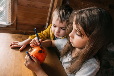 Close up kids painting the halloween pumpkin at home. Preparing celebration at homeの写真素材