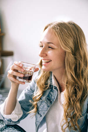 Close up portrait of an attractive blonde millennial woman sitting in a cafe, drinking coffee and laughs Breakfast time. Urban styleの写真素材