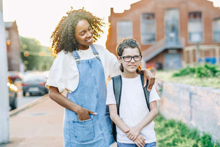 Young school teacher tutor hugs autism boy while walking back to school. Protecting and supporting autism children conceptの写真素材