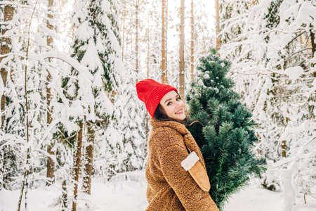 Winter activity lifestyle getting ready for Christmas. An attractive young woman carries a Christmas...