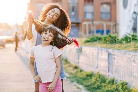 Babysitter young woman and cute little girl having fun together outside. Children leisure activities, babysitting conceptの写真素材