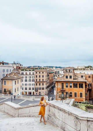 Rome Italy tourism concept. Young woman in orange outfit stay overlooking Rome. Spanish stepsの写真素材
