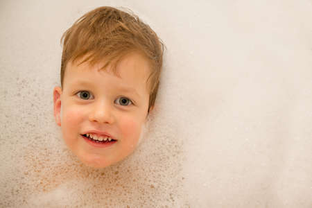 A baby in a bathtub with soap foam 