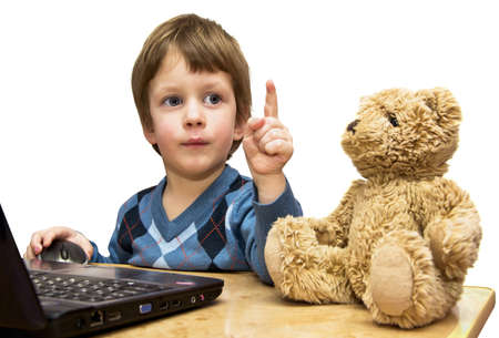 The boy teaches a toy bear in front of the laptopの写真素材