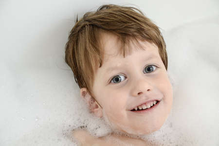 A baby in a bathtub with soap foam 