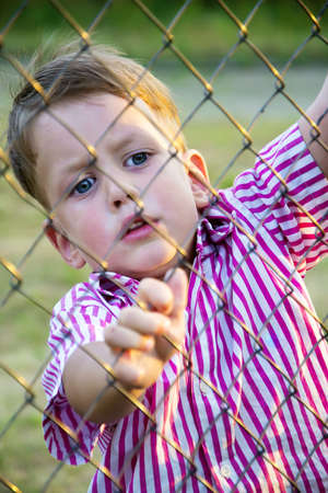 boy behind mesh fenceの写真素材