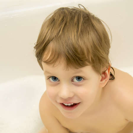 Cute boy taking a bath with foam