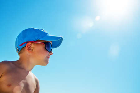 Beautiful child wearing blue cap on beachの写真素材